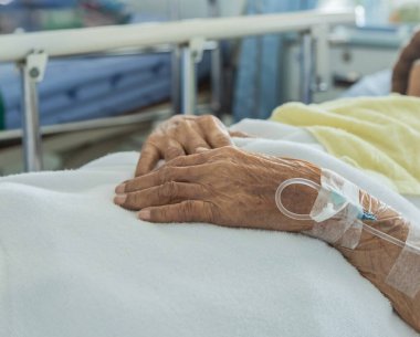Enjeksiyon için damar içi serum fizyolojisini kapatın. Hastanenin yatak odasında yatan yaşlı bir hastanın elinde.