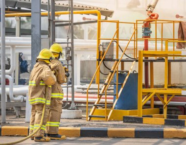 professional firemans brave buddy team assistance in yellow fire fighter uniform holding fire hose nozzle spraying foam  water control fighting in the industrial factory clipart