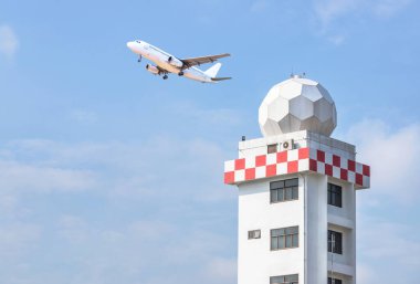 Havacılık meteorolojik gözlem istasyonu kulesi ya da hava gözlem kulesi radar kulesi ya da hava radar kubbesi mavi gökyüzünde uçan yolcu uçağıyla havaalanında hava durumu. 