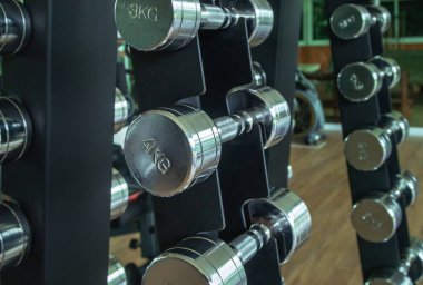 metal dumb bells on rack in sport fitness center