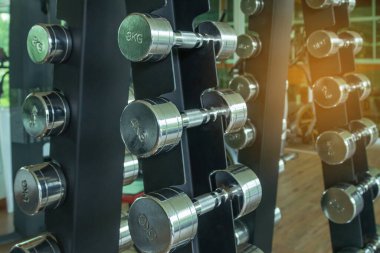 Close up row of metal dumb bells for bodybuilding muscle growth on rack in sport fitness center 