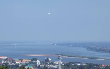 Aerial  landscape view above Mukdahan city with Ho Kaeo tower while white passenger airplane landing to Savannakhet airport Laos over Mekong river border between Thai - Laos  clipart