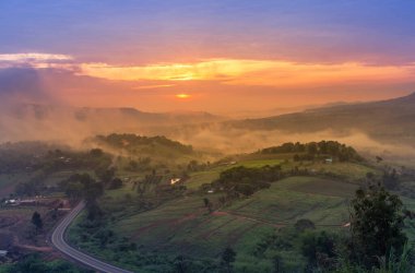 Khao Takhian Ngo 'dan sis perdesiyle, şehir yolu üzerindeki yüksek açılı manzara. Sabahleyin Khao Kho, Phetchabun Tayland' da güneş doğarken..