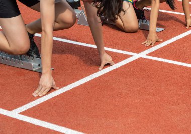 Stadyumdaki koşu pistinde yarış için ellere hazırlanan bayan sporcular