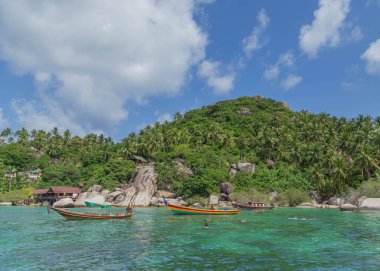 Tahta kuyruklu tekneler denizde kalırken turistler Koh Tao adasında dalışın keyfini çıkarıyorlar.