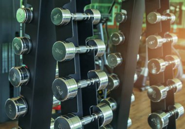 Close up row of metal dumb bells for bodybuilding muscle growth on rack in sport fitness center ,healthy lifestyle concept .