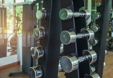 Close up row of metal dumb bells for bodybuilding muscle growth on rack in sport fitness center ,healthy lifestyle concept .