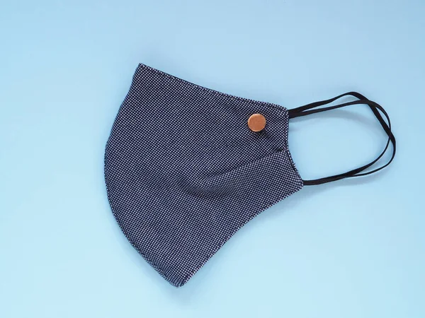 Top view, Dark blue fabric face mask to prevention pollution and viruses. DIY handmade from cotton muslin on blue background. Healthcare, Medical and New normal concept. Copy space for your text
