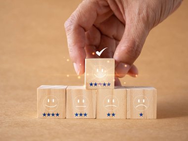 Müşteri hizmetleri ve memnuniyet derecelendirme konsepti. Müşteriler beş yıldızlı gülen yüz bloğu ya da kahverengi arka plandaki en iyi servisi seçiyorlar. Yüksek kaliteli ürün veya servisimizin reytingleri