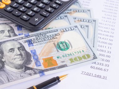 İş ve finansal konsept. Para geçmişi, 100 dolarlık banknotlar, finansal rakamların listesi, iş yerindeki hesap makinesi. Yakın plan, Kâr, Tasarruf, Finans ve Servet
