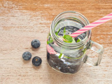 Üst manzara, taze organik yaban mersinli kaynaşmış su ve ahşap arka planda saman içmek. Mesajın için yer aç. Üst manzara, düz uzanma