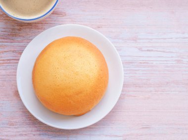Beyaz tabakta ev yapımı Meksika vanilyalı çöreği (kahve ekmeği) ve kırsal masada kahve fincanı. Metnin için boşluk