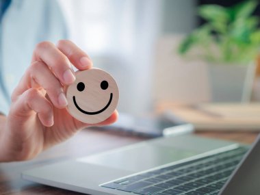 Gülen ikonlu el ele tutuşan ahşap blok. Müşteriler olumlu eleştiriler ve tavsiyelerde bulunuyor. Pozitif düşünce, memnuniyet derecelendirme kavramı.