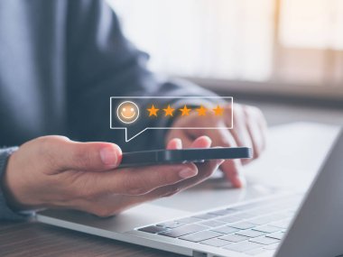Müşteri hizmetleri ve memnuniyet derecelendirme konsepti. Müşteriler sanal ekrandaki beş yıldızlı gülen yüzü akıllı telefon uygulamasına ya da en iyi servise tercih ediyorlar. Geri bildirim incelemesi, iyi kalite.