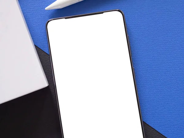 青い黒い紙の背景に白い画面とスタイラスペンでトップビュー フラットレイアウト モックアップスマートフォン 携帯電話 製品広告 オンラインビジネスのためのテンプレート — ストック写真