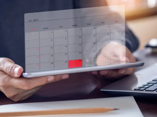 stock image Businessmen use tablet pc show calendar application on virtual screen showing May 2023 and mark red color on the date 31st. Calendar app with planning and reminder concept. Business background.