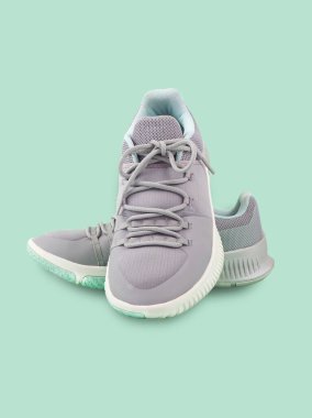 Yeşil arka planda, erkekler ve kadınlar için modern gri-açık yeşil spor ayakkabılar (unisex) izole edilmiştir. Moda tarzı spor ayakkabıları, spor ayakkabısı tasarımı için model, spor ürünleri.. 