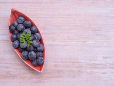 Üst manzara, beyaz ahşap arka planda yapraklı kırmızı plakalı taze yaban mersini. Fotokopi alanı olan düz bir yer. Sağlıklı yeme ve beslenme kavramı, Superfood