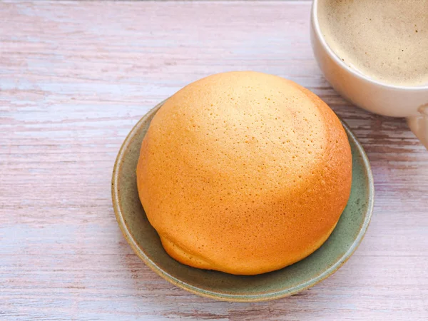 Homemade mexican vanilla bun (coffee bun) on turquoise clay round plate and coffee cup over rustic table. space for your text