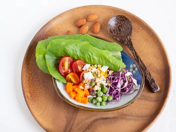 Healthy food and  weight loss concept. Homemade mixed salad, almond in oval plate and spoon on wooden background. Top view, with copy space.