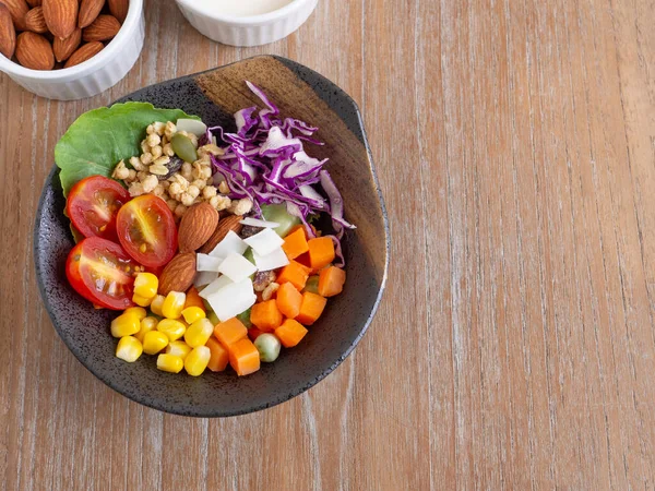 Healthy food and  weight loss concept. Homemade mixed salad, almond in old clay bowl on wooden background. Top view, with copy space.
