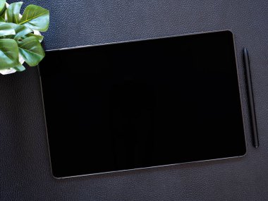 Üst Manzara. boş siyah ekran ve kablosuz kalemli düz konum dijital tablet bilgisayar, siyah deri zemin üzerinde küçük ağaç.