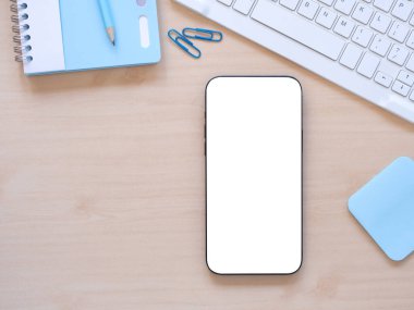 Düz konum, bembeyaz ekran akıllı telefon, klavye, defter ve kalem, açık tahta arka planda. İnternet alışverişi, blog, logo, ürün ve sosyal medya kavramları.  