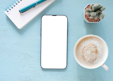 Model, kahve fincanı, kaktüs, kalem ve mavi iş yerindeki defter için izole edilmiş boş cep telefonu beyaz ekranı. Üst görünüm bileşimi. Konsept alışverişi, blog, logo, ürün ve sosyal medya