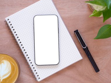 Üst manzara, düz beyaz ekran akıllı telefon dizüstü bilgisayar, kahve fincanı, kalem, tahta masaüstüne bitki. Konsept pazarlama, logo, ürün ve web afişi, çevrimiçi alışveriş