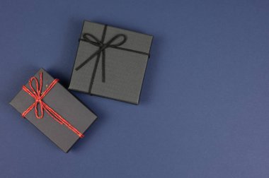 Mutlu yıllar için hediye kutusu konsepti, teşekkürler, tebrikler, anneler günü, yıldönümü ve tatil. Koyu mavi arkaplanda siyah hediye kutusunun kopyalama alanı olan üst görünüm.