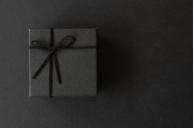 Doğum günün kutlu olsun, teşekkürler, tebrikler, yıldönümü, sevgililer günü. Üst görünüm, siyah hediye kutusunun düz yatağı siyah kağıt arka planda siyah halatla bağlanmış..