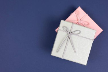 Üst manzara, gri hediye kutusu, pembe hediye kutusu ve koyu mavi kağıt arka plan. Doğum günü konsepti için hediye kutusu, teşekkürler, tebrikler, anneler günü, yıldönümü, sevgililer günü.