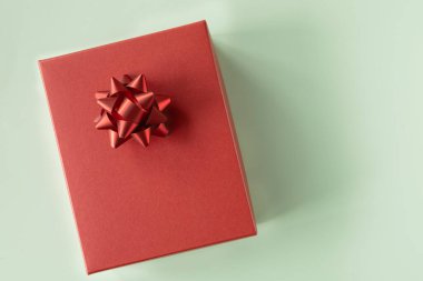 Kırmızı hediye kutusu, yeşil arka planda kırmızı fiyonk. Üst manzara, fotokopi alanı olan düz bir yer. Tatil kavramı.