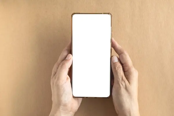El ele tutuşan akıllı telefon, kahverengi arka planda beyaz bir ekran gösteriyor. Üst manzara, fotokopi alanı olan düz bir yer. Çevrimiçi iş, blog yazarı ve reklamcılık kavramı