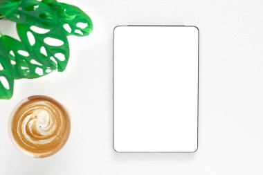Beyaz ekranlı dijital tabletin şablonu ve beyaz ahşap arka planda kahve fincanı. Konsept alışverişi, blog, logo, ürün ve sosyal medya. Kopyalama alanı olan üst görünüm.