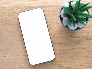 Mokup, ahşap arka planda beyaz ekranı olan modern bir akıllı telefonun yer aldığı minimalist düz konum şablonu. Konsept alışverişi, blog, logo, ürün ve sosyal medya