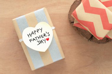 Üst manzara, hediye kutusu dikdörtgen şeklinde kahverengi ve gümüş renkli çizgilerle sarılı. Beyaz kalp şeklinde bir etiket, üzerinde 