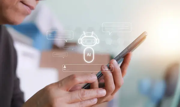 Akıllı telefon tutan biri, bir konuşmayı temsil eden konuşma baloncuklarıyla çevrili yapay zeka sohbet robotu arayüzü ile etkileşime geçiyor. Yapay zeka kavramı, yapay zeka yardımcı teknolojisi.