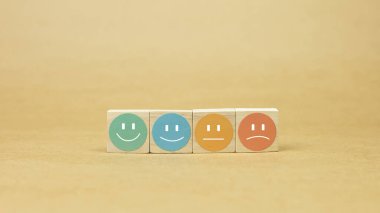 Dairesel etiketli dört tahta blok ve farklı bir ifade şekli, görsel olarak bir duygu spektrumunu ya da memnuniyet seviyesini temsil ediyor. Müşteri geribildirim kavramı, tatmin oranları, anketler