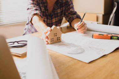 Mimarın eli, inşaat ofisindeki inşaatın planını kullanarak tasarım yapıyor.