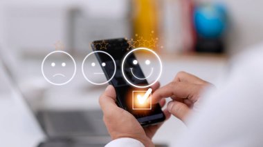 Müşteri hizmetleri değerlendirme konsepti. Akıllı telefon kullanmak, sanal ekranda gülümseyen yüz ifadelerine basmaktır..