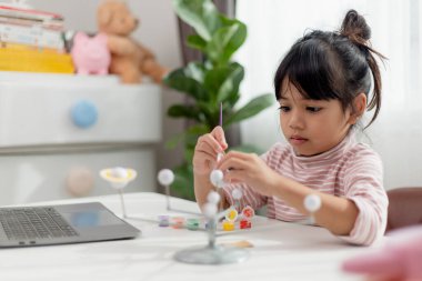 Küçük Asyalı kız coğrafya dersinde güneş sistemini inceliyor. Gezegenlerin ölçekli modeline bakıyorum.
