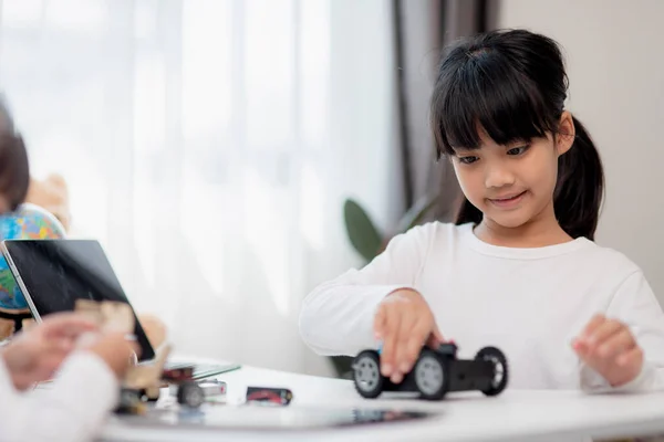 Two Asian students learn coding robot cars and electronic board cables in STEM, STEAM, mathematics engineering science technology computer code in robotics for kids concepts.