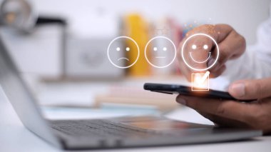 Müşteri hizmetleri değerlendirme konsepti. Akıllı telefon kullanmak, sanal ekranda gülümseyen yüz ifadelerine basmaktır..