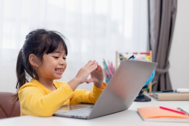 Okuldaki ilk günüm. Asyalı küçük kız dizüstü bilgisayar kullanıyor, online e-öğrenme sistemini inceliyor..