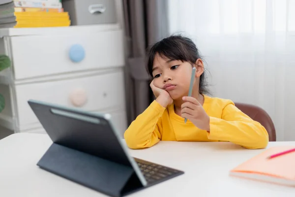 stock image Little Asian girl sitting alone and looking out with a bored face, Preschool child laying head down on the table with sad bored with homework, spoiled child