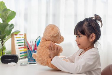 Çocuk oyuncak ayıyla oynuyor. Asyalı küçük kız en sevdiği oyuncağına sarılıyor. Çocuk ve peluş hayvan evde.. 