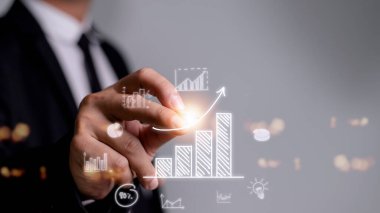 İş adamı artan bir eğilim oku ve plandan hedefe yükselen bir tablo çiziyor. Kurumsal yatırım geliştirme fikrinin bir temsili..