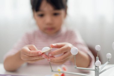 Küçük Asyalı kız coğrafya dersinde güneş sistemini inceliyor. Gezegenlerin ölçekli modeline bakıyorum.