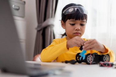 Asyalı öğrenciler evlerinde robot arabaları ve elektronik tahta kablolarını STEM, STEAM, matematik mühendisliği, bilim teknolojisi bilgisayar kodlarını çocuk konsepti için robotikte kodlayarak öğreniyorlar..